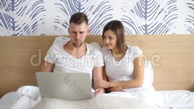 年轻夫妇带着笔记本电脑<strong>在床上</strong>看电影